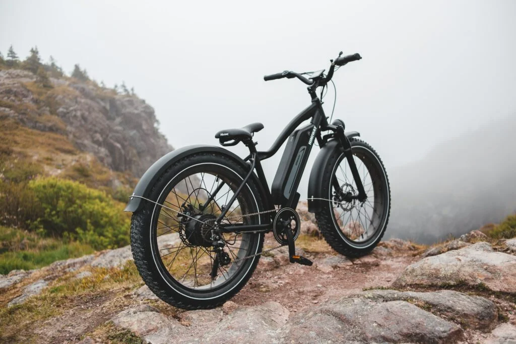 A mountain bike is parked on top of a rocky mountain, showcasing its impressive durability and maneuverability in challenging terrains.