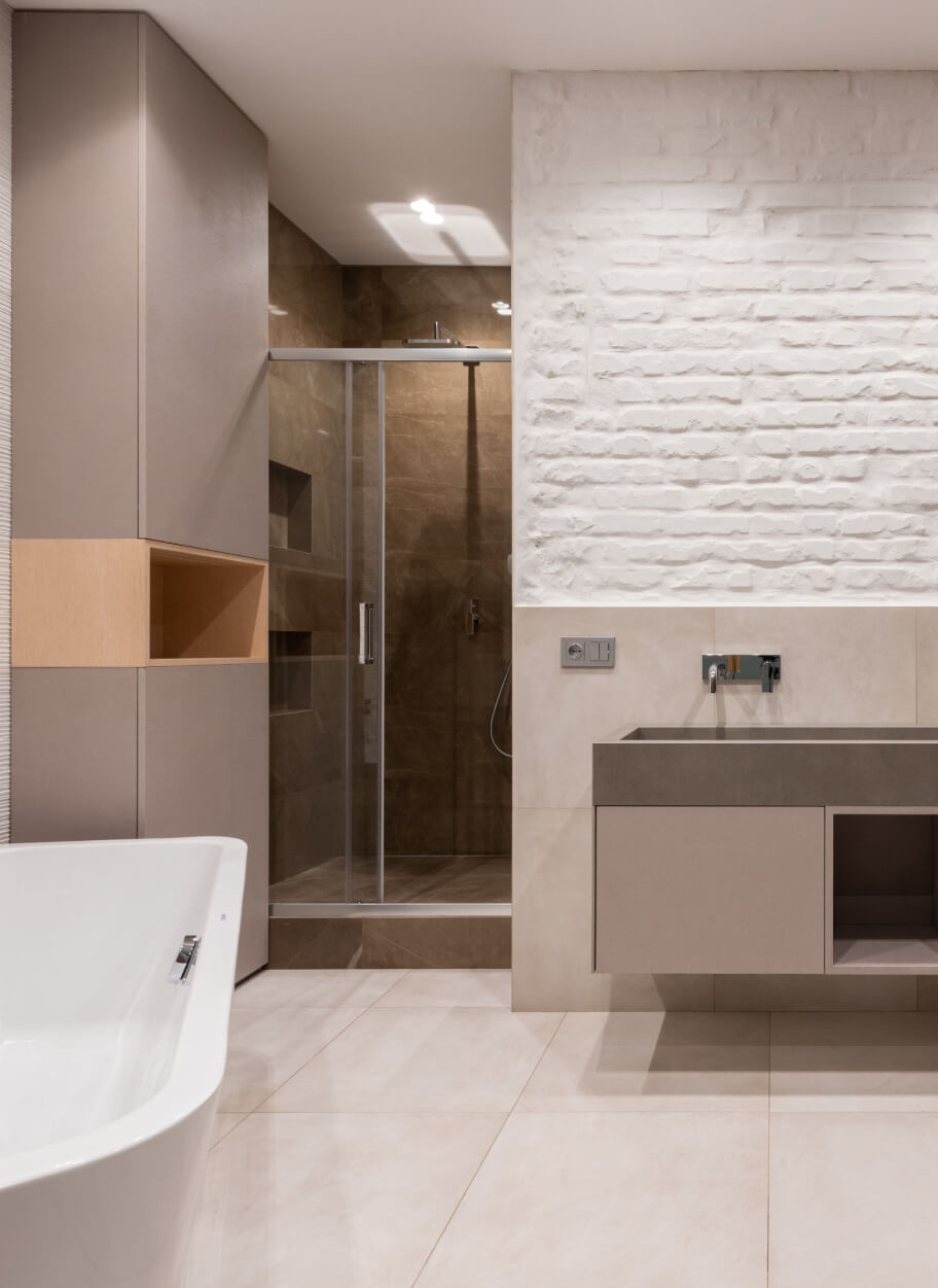 A modern bathroom with beige walls and a white tub.