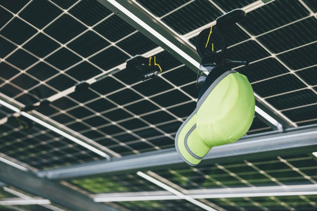 A yellow hard hat hangs from a fixture beneath the innovative Sunpower Maxeon 6 solar panels.